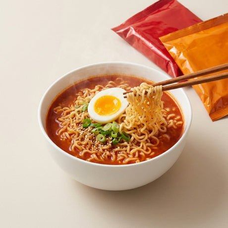 Kom instant noodles met ei en lente-ui, met twee ongeopende zakjes ernaast